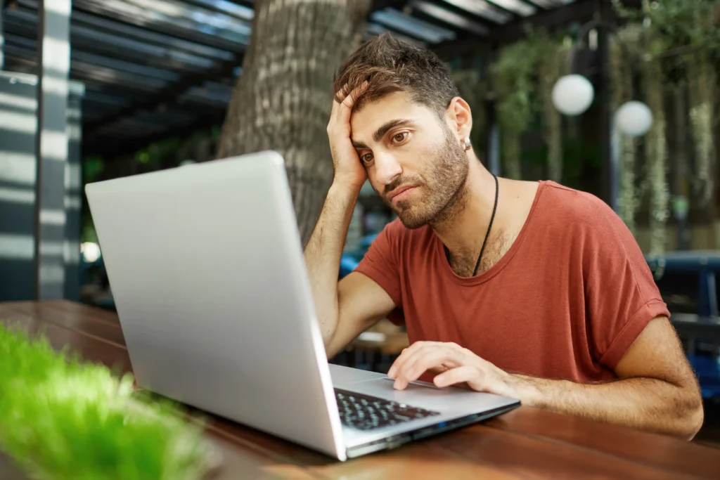Frustrated user waiting for a slow laptop to respond, illustrating poor laptop performance and computer speed issues.