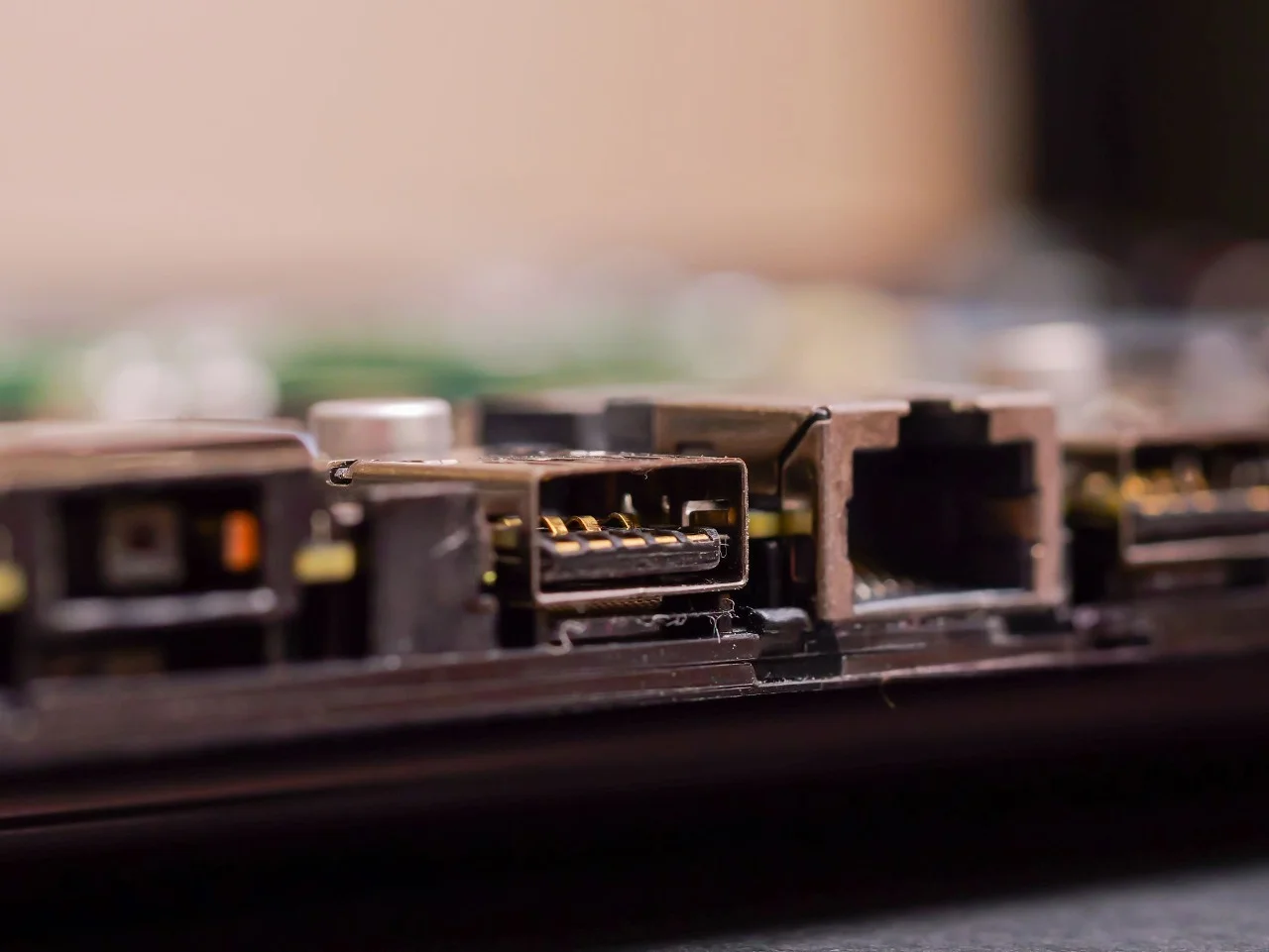 Close-up view of a damaged laptop charging port and surrounding connectors, illustrating how to know if a laptop charging port is damaged when a laptop won't charge.