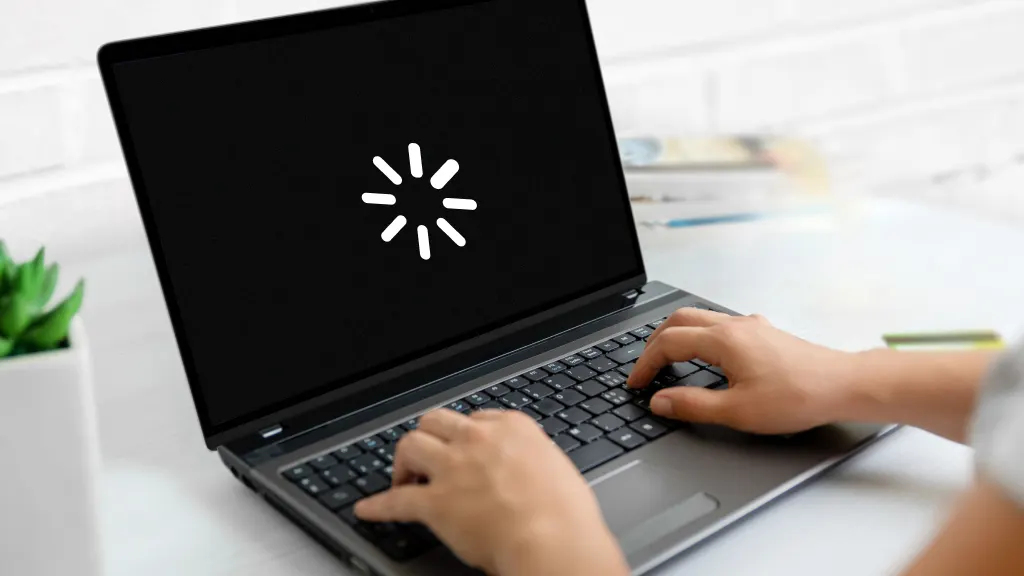 Laptop with a black screen featuring a white loading icon, showing freezing screen