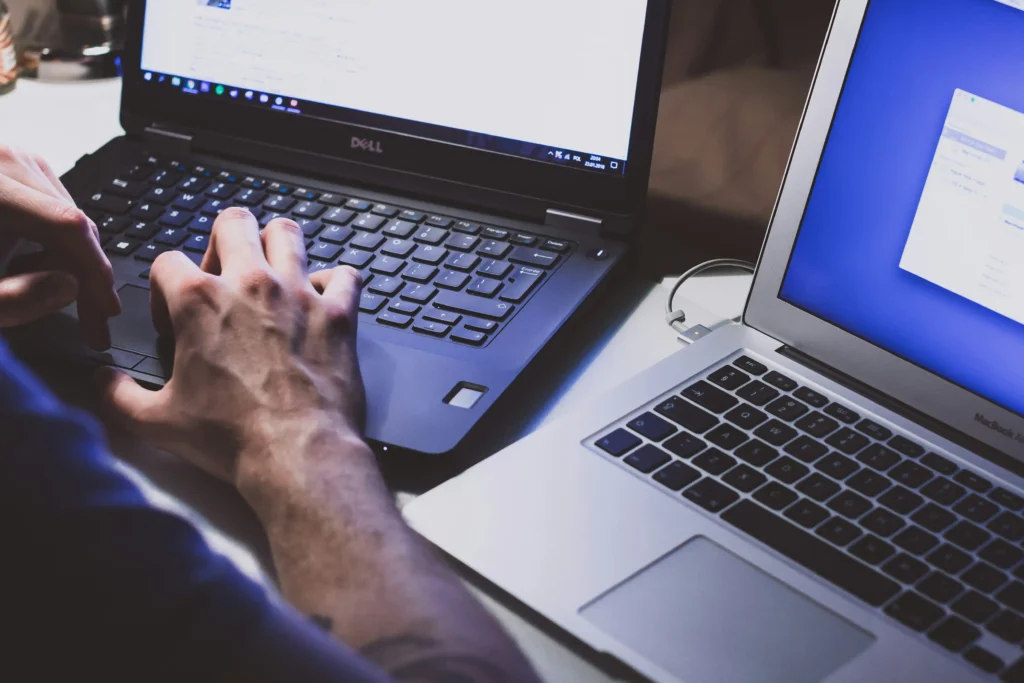 User working with multiple laptops while troubleshooting persistent display and black screen issues.