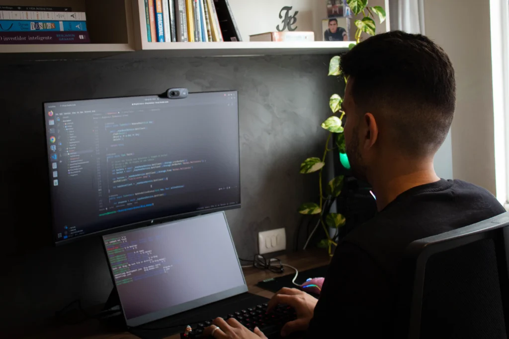 Person working on a laptop connected to an external monitor, illustrating an external display setup for troubleshooting laptop screen issues.