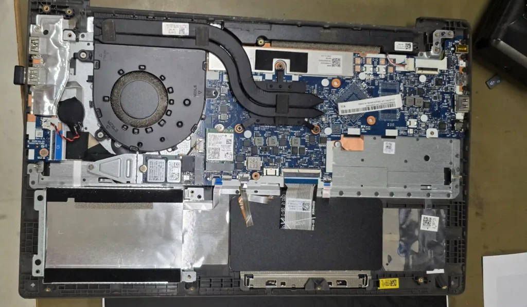 Top-down internal view of an opened Lenovo laptop featuring the motherboard, cooling fan, heat sink assembly, and M.2 SSD slot.