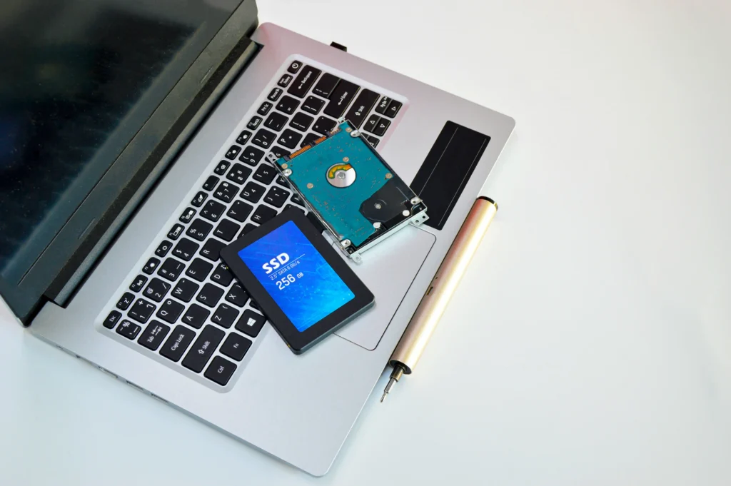 A 256 GB solid-state drive (SSD) with a blue label displaying its storage capacity, placed on the keyboard of a silver laptop alongside a precision screwdriver. The image highlights an SSD storage device used for storing files, upgrading laptop storage and improving data access speeds.